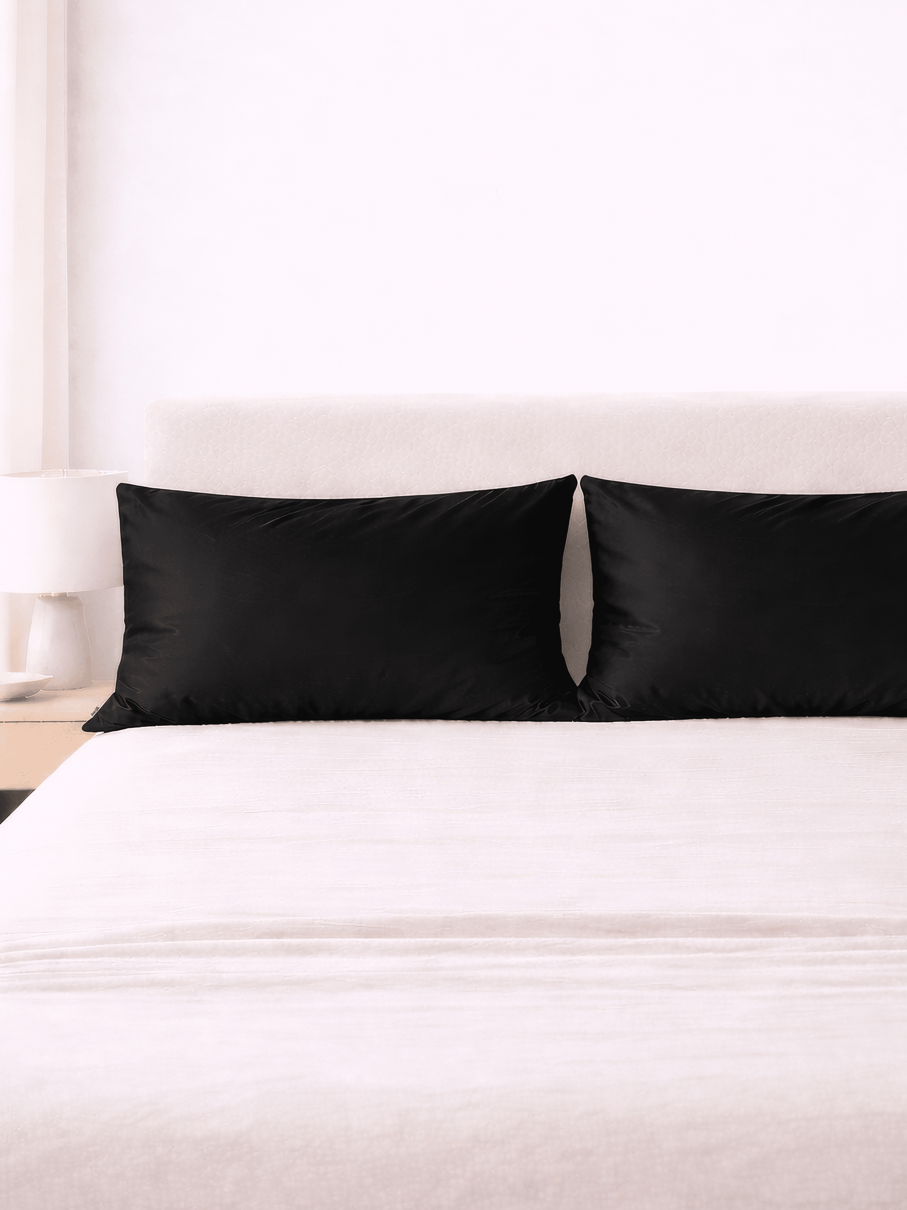 two black king size silk pillowcases sitting on bed