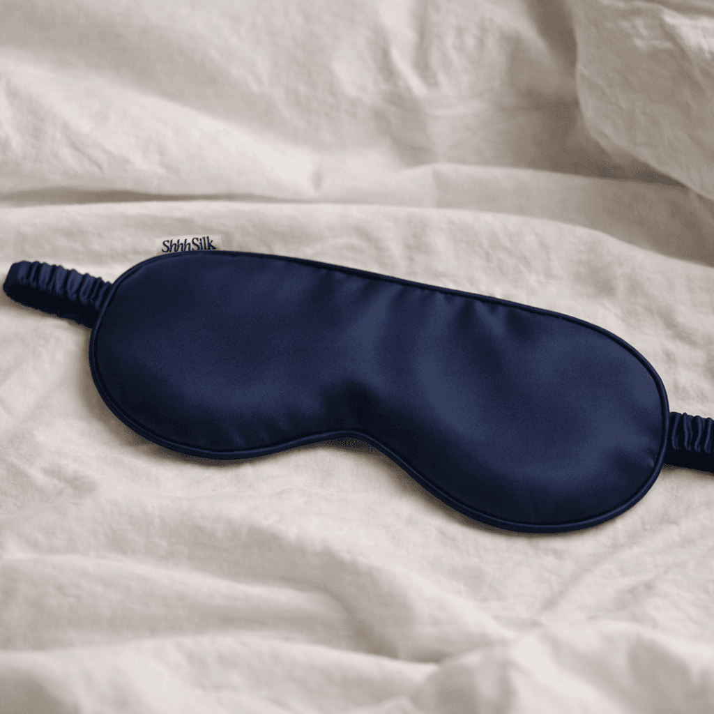 Navy silk sleep mask on a white textured surface