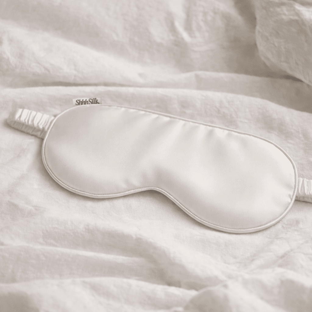 White silk sleep mask on a soft fabric background
