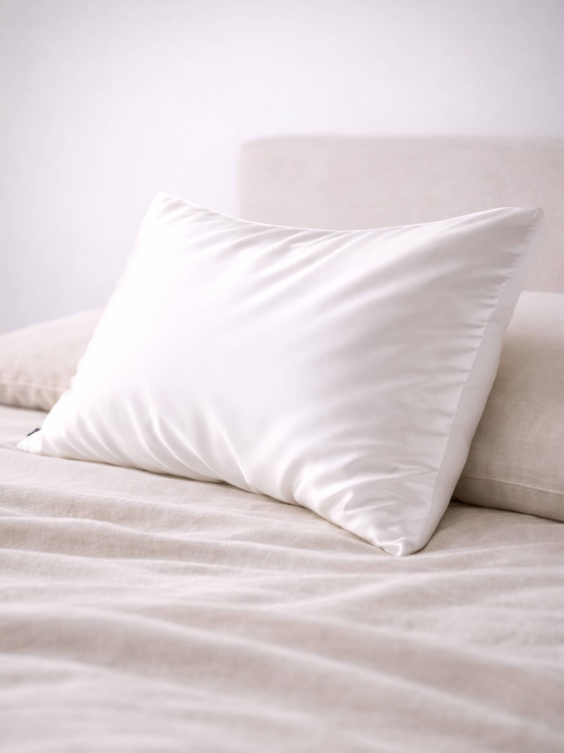angled shot of a queen size pure white silk pillowcase on a bed